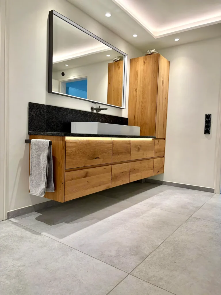 Modernes Badezimmer mit großformatigen Bodenfliesen in Betonoptik und Waschtisch aus Eiche