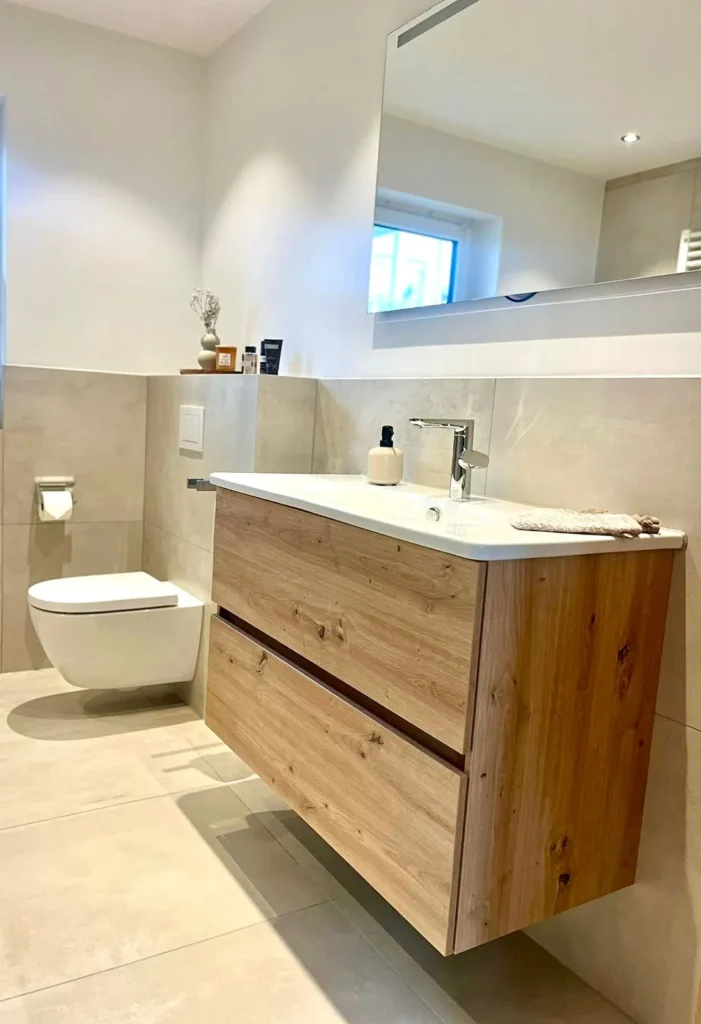 Badezimmer mit Holz-Waschtisch, Spiegel und großformatigen Wand- und Bodenfliesen