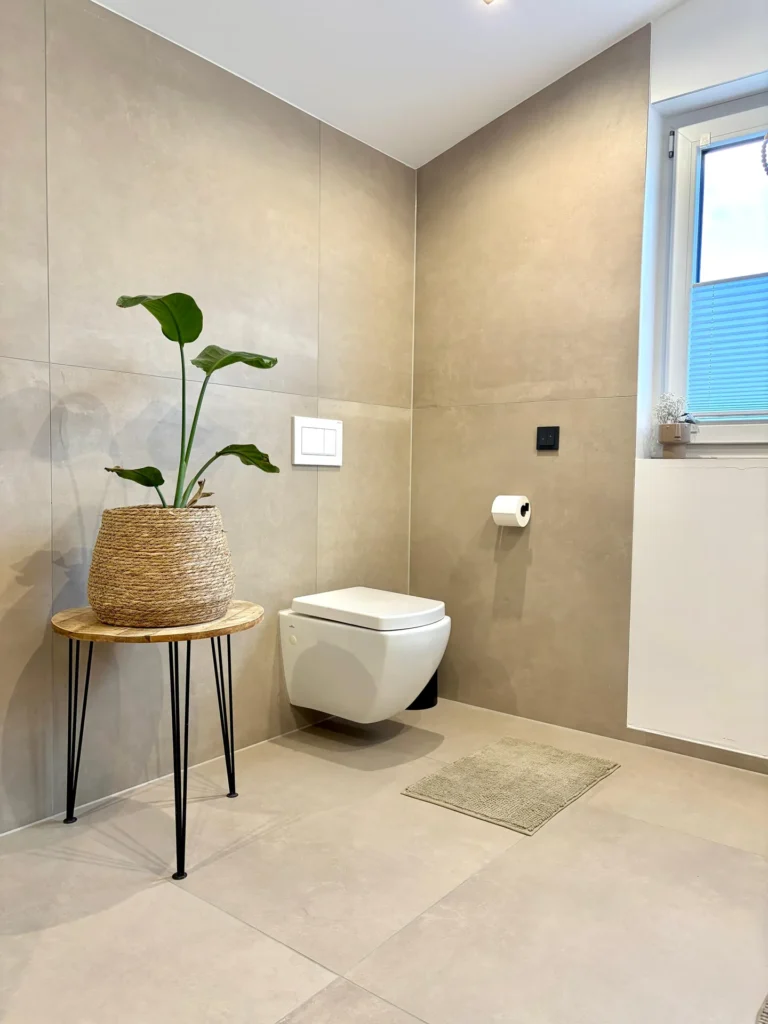 Badezimmer mit wandhängendem WC und beigen Großformatfliesen an Wand und Boden