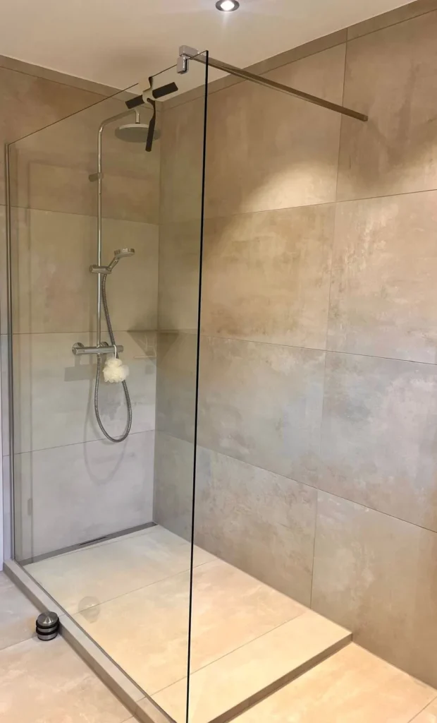 Dusche mit Glaswand und großformatigen Wandfliesen in Sandsteinoptik
