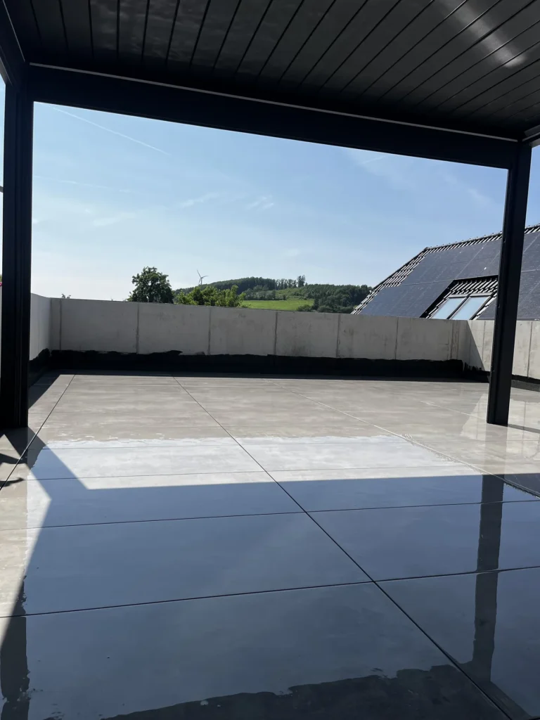 Überdachte Terrasse mit großformatigen Terrassenfliesen und Ausblick ins Grüne