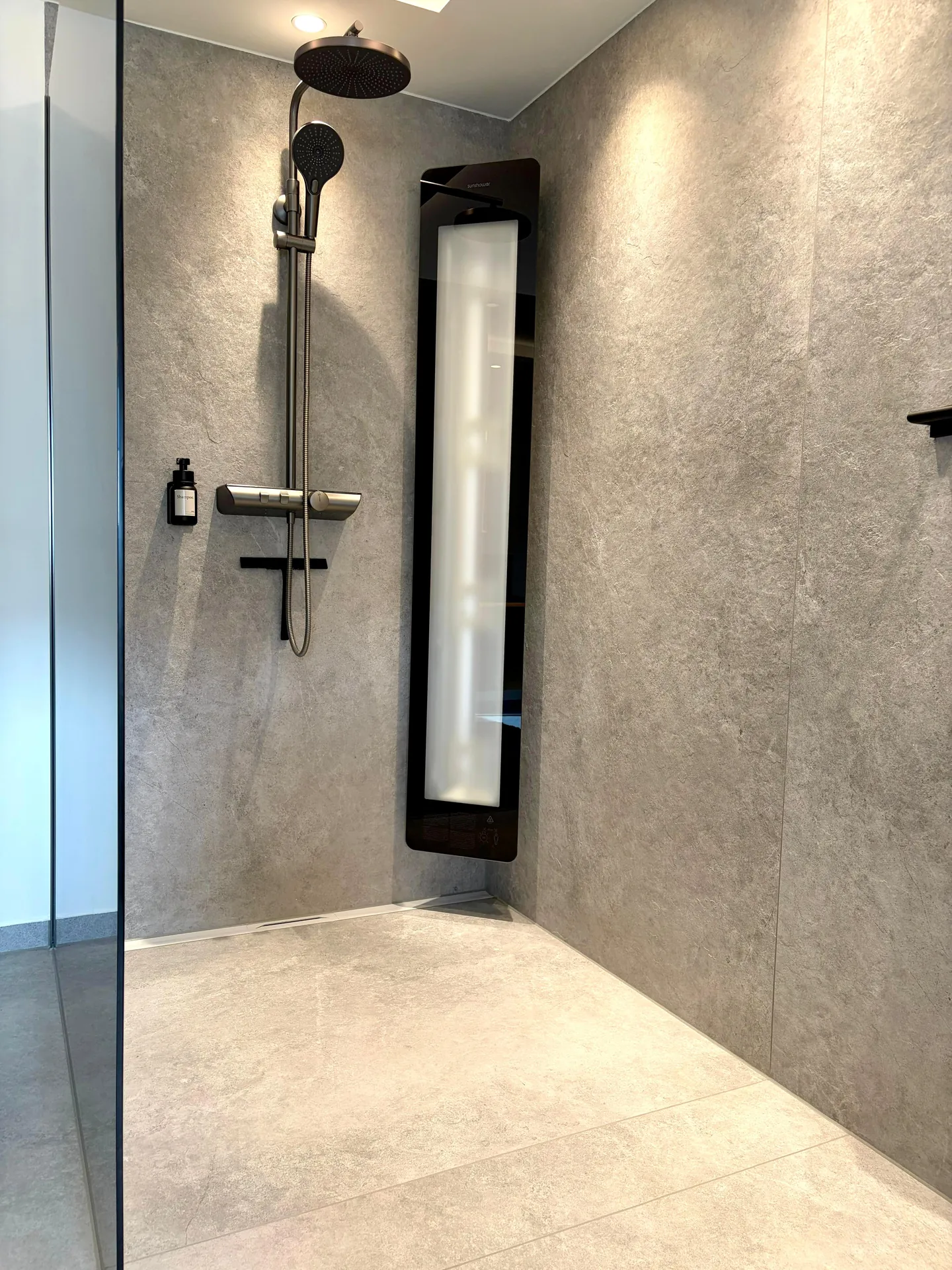 Bodengleiche Walk-in-Dusche mit großformatigen Wandfliesen in Steinoptik